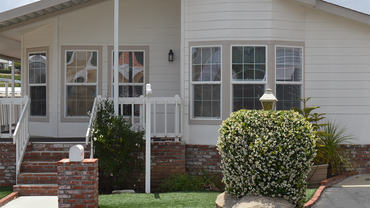 Double wide manufactured home with white siding and beige trim windows located in Lake Forest California