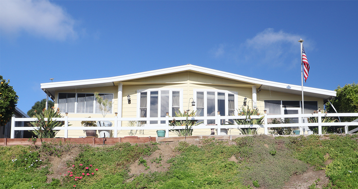 yellow and white manufactured home with with white fence on land that does not qualify for conventional lending